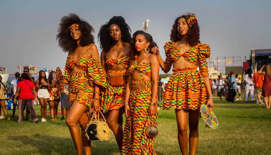 Four women in matching kente outfits on the festival grounds at Afrochella