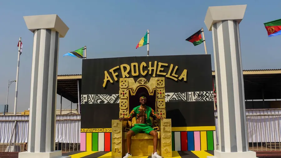 A man seated on a large golden throne installation at Afrochella