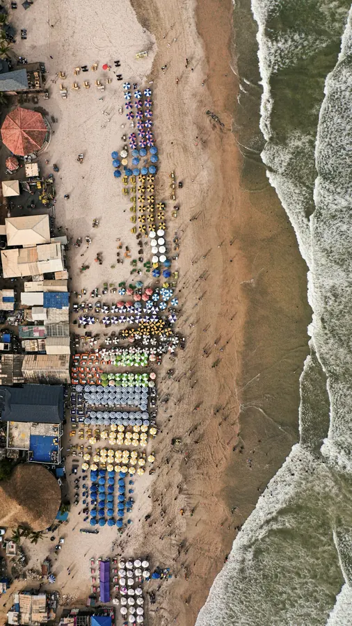 Labadi Beach from above: rows of umbrellas and chairs along the sand, with waves breaking