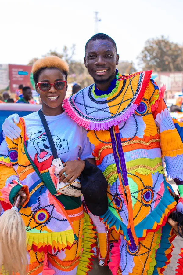 Two masqueraders in colourful patchwork costumes smiling for the camera