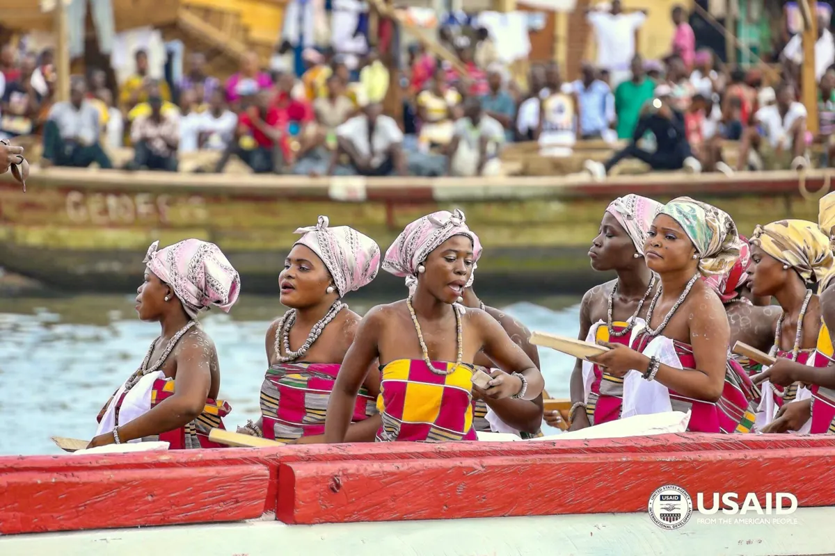 Women in white headwraps in a canoe on the lagoon at Bakatue