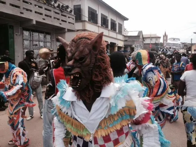 A masquerader in a costume and animal mask at Bakatue