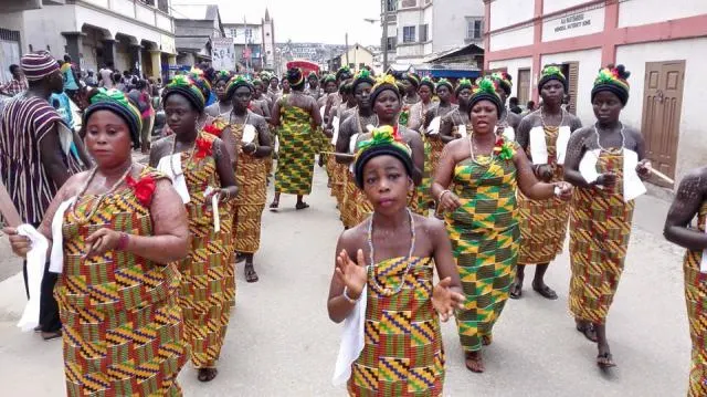Women in kente walking in procession through Elmina at Bakatue