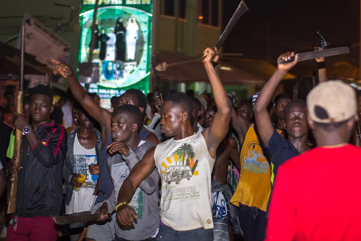 Young people raise sticks and torches at the fire festival in Tamale