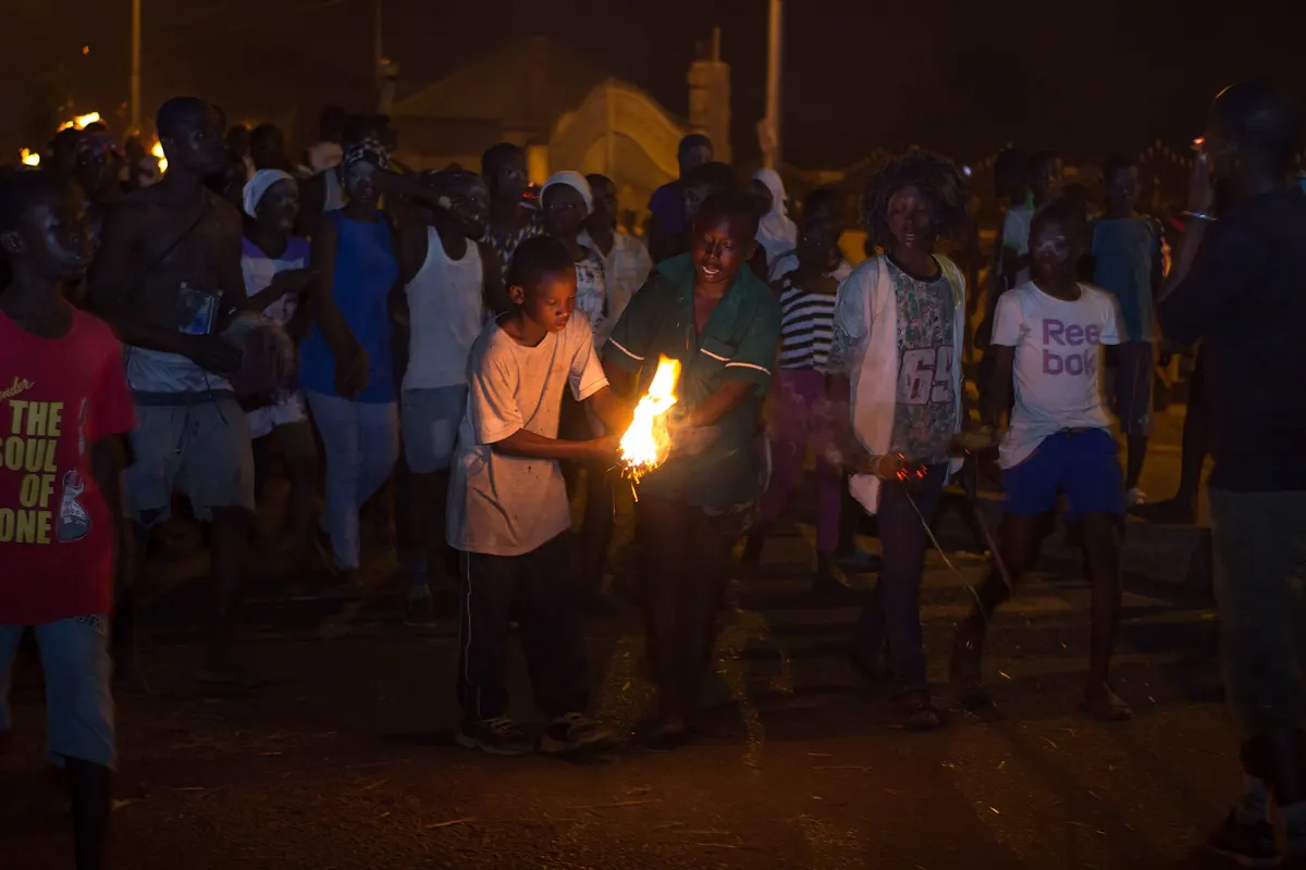 A street at night with torches carried through the crowd