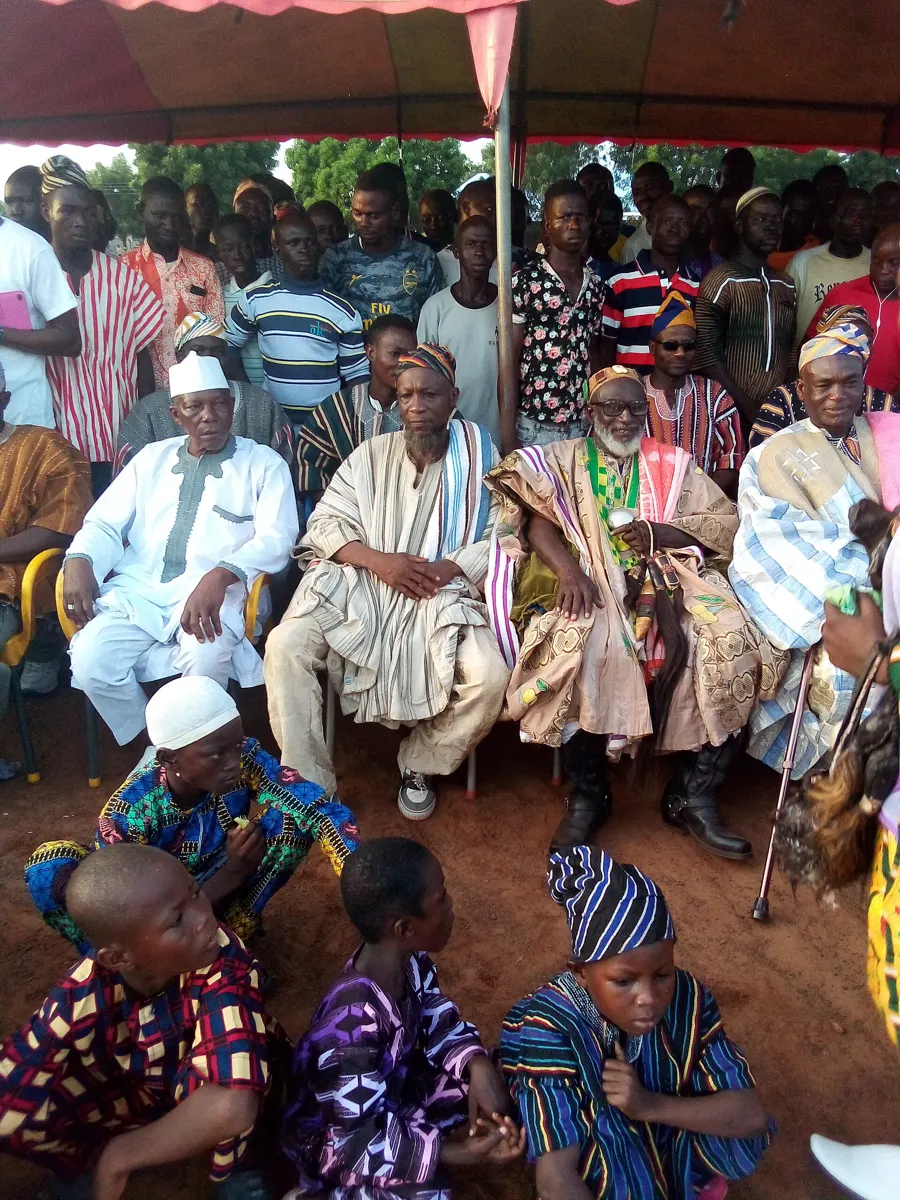 Elders in smocks seated under a canopy at Damba