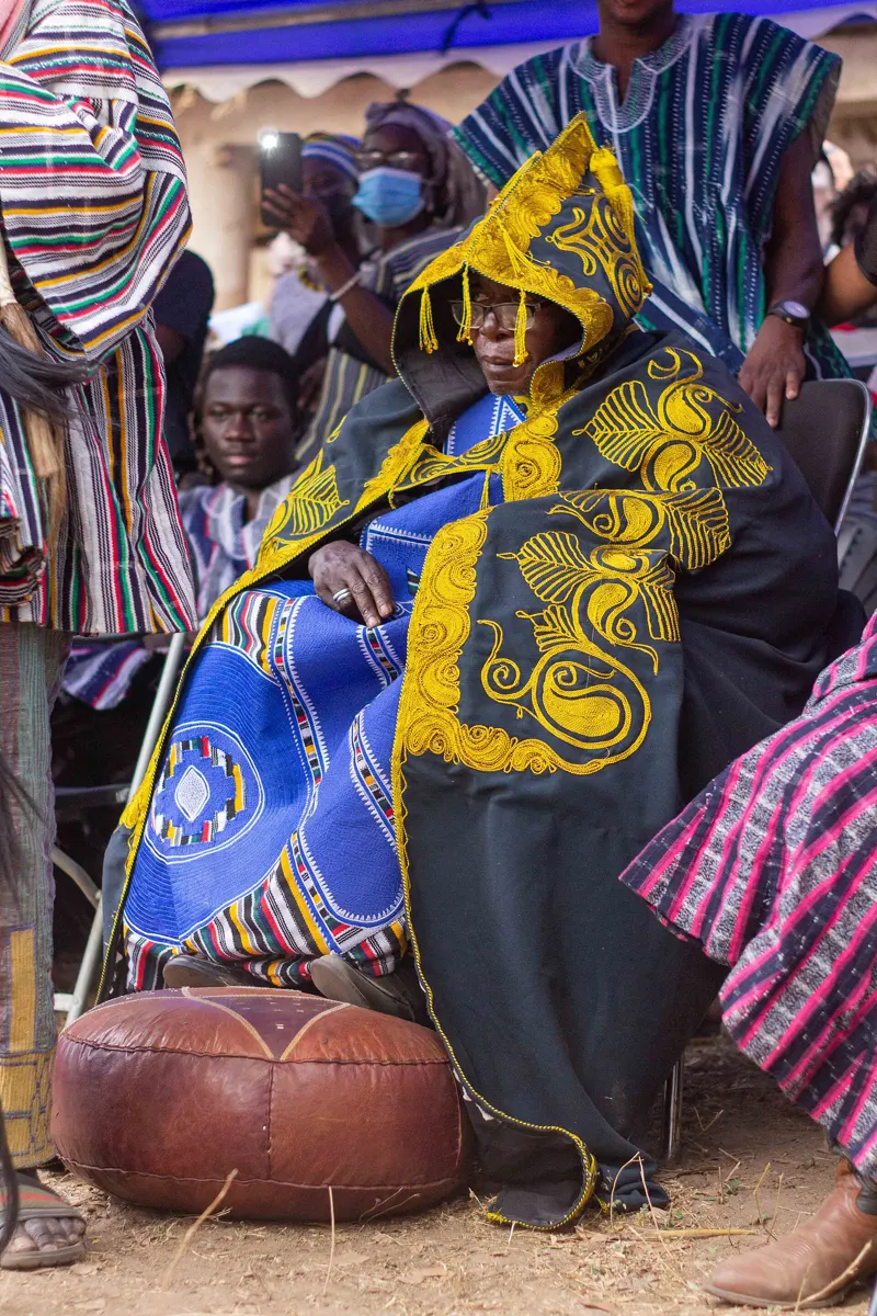 A chief in a blue and yellow robe seated at Fiok