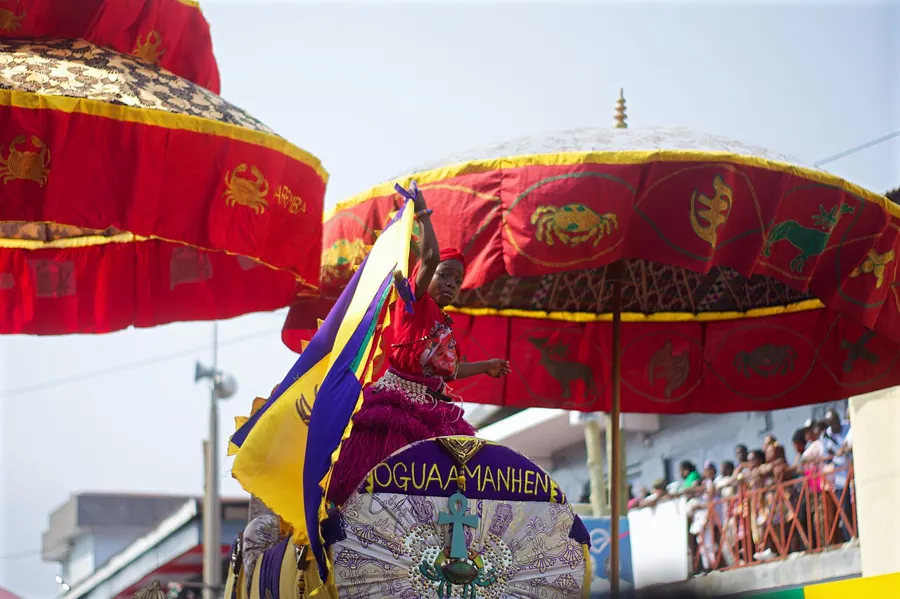 Red and gold state umbrellas over a chief in a palanquin at Fetu Afahye