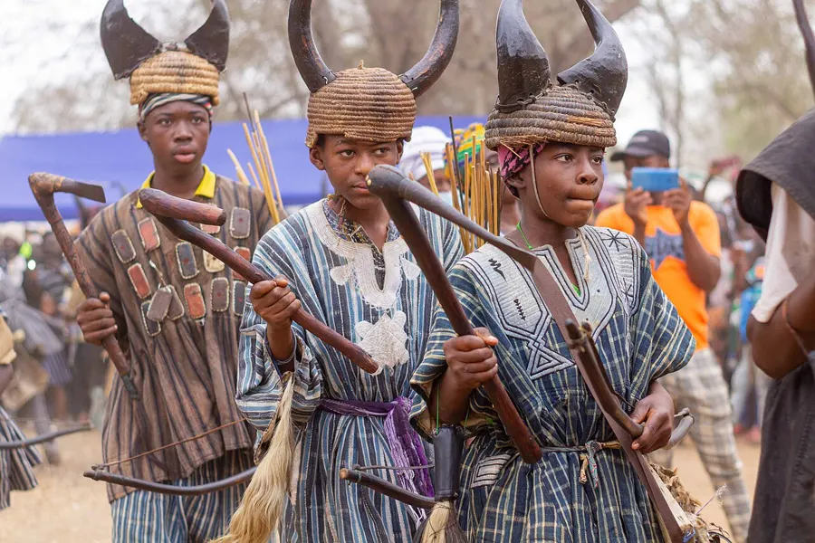 Young Builsa warriors in horned headdresses with traditional weapons at Fiok