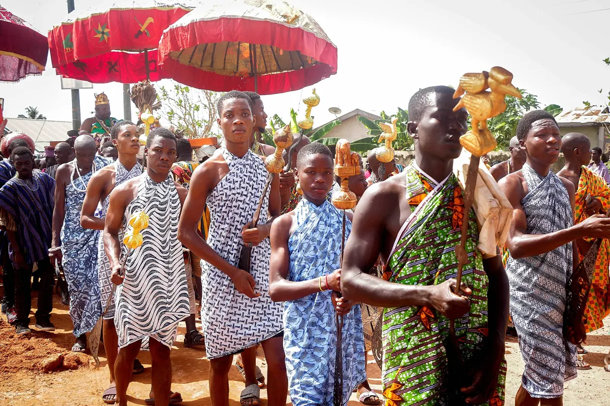 Young men lead the chief under red umbrellas to the Ngmayem grounds