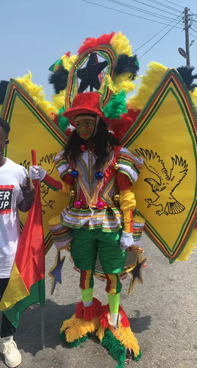 A masquerader in a feathered red, green and yellow costume